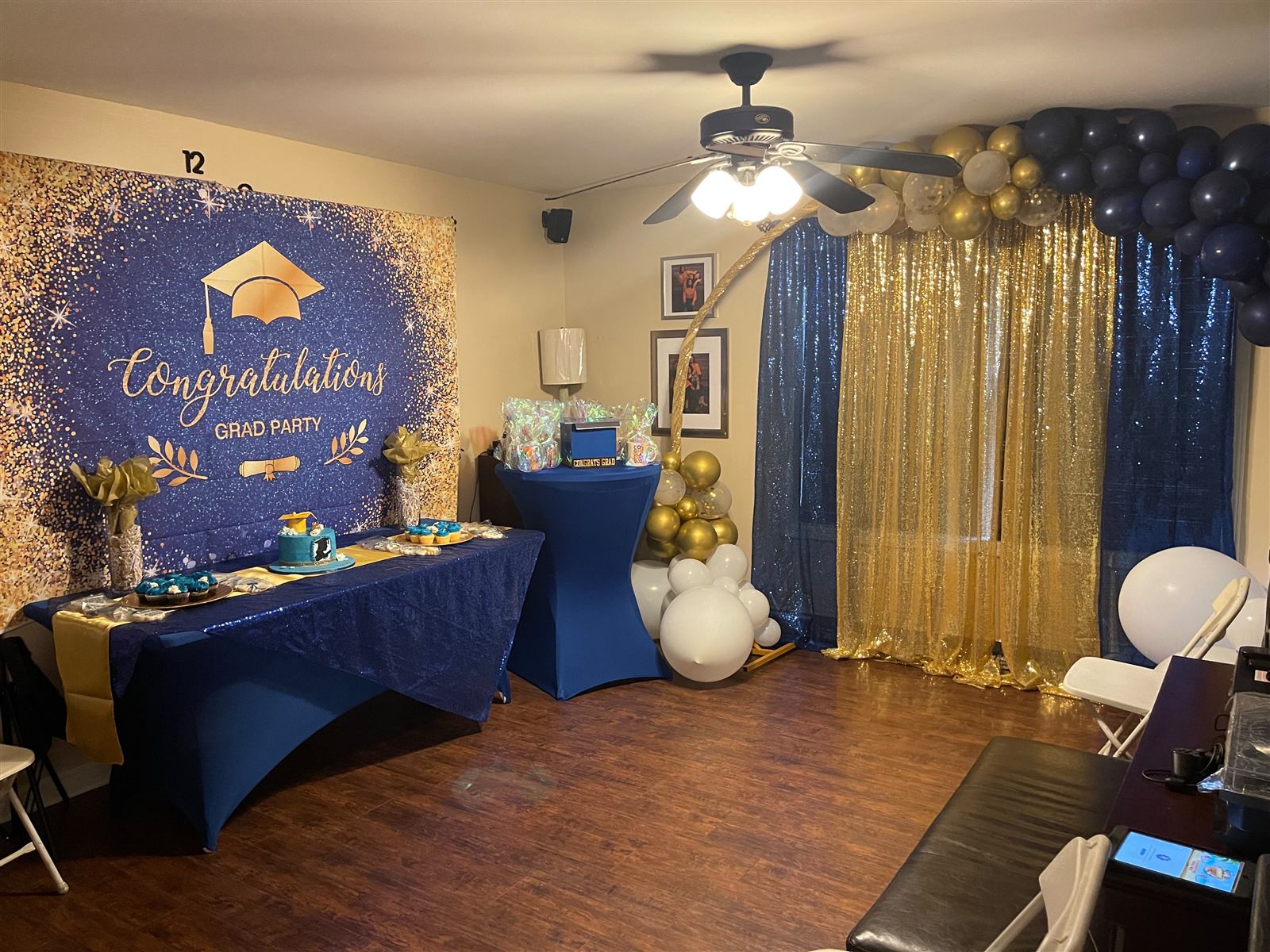 Full graduation party room with navy and gold sequin backdrop and balloon garland