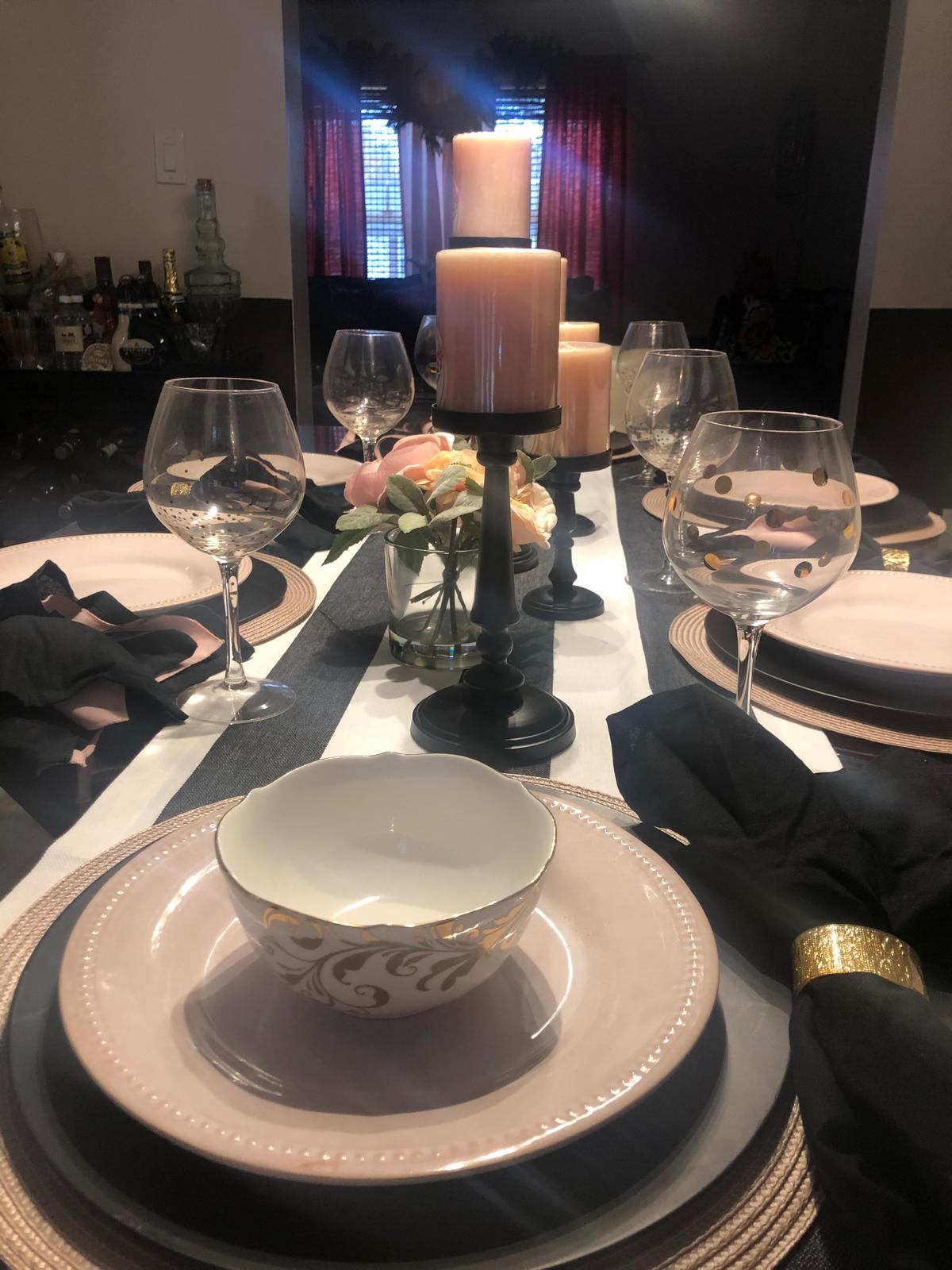 Elegant blush, black, and gold place setting with candles and roses