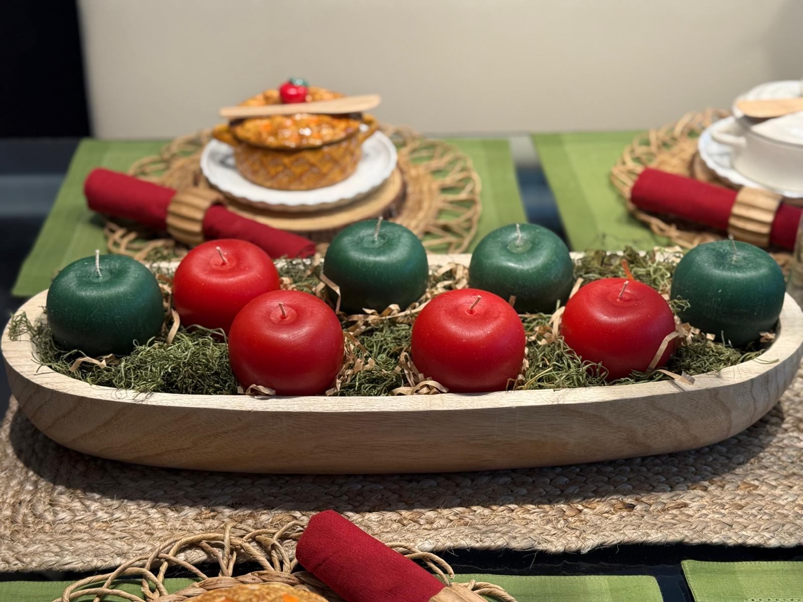 Close-up of apple pillar candles nestled in moss in a wood tray