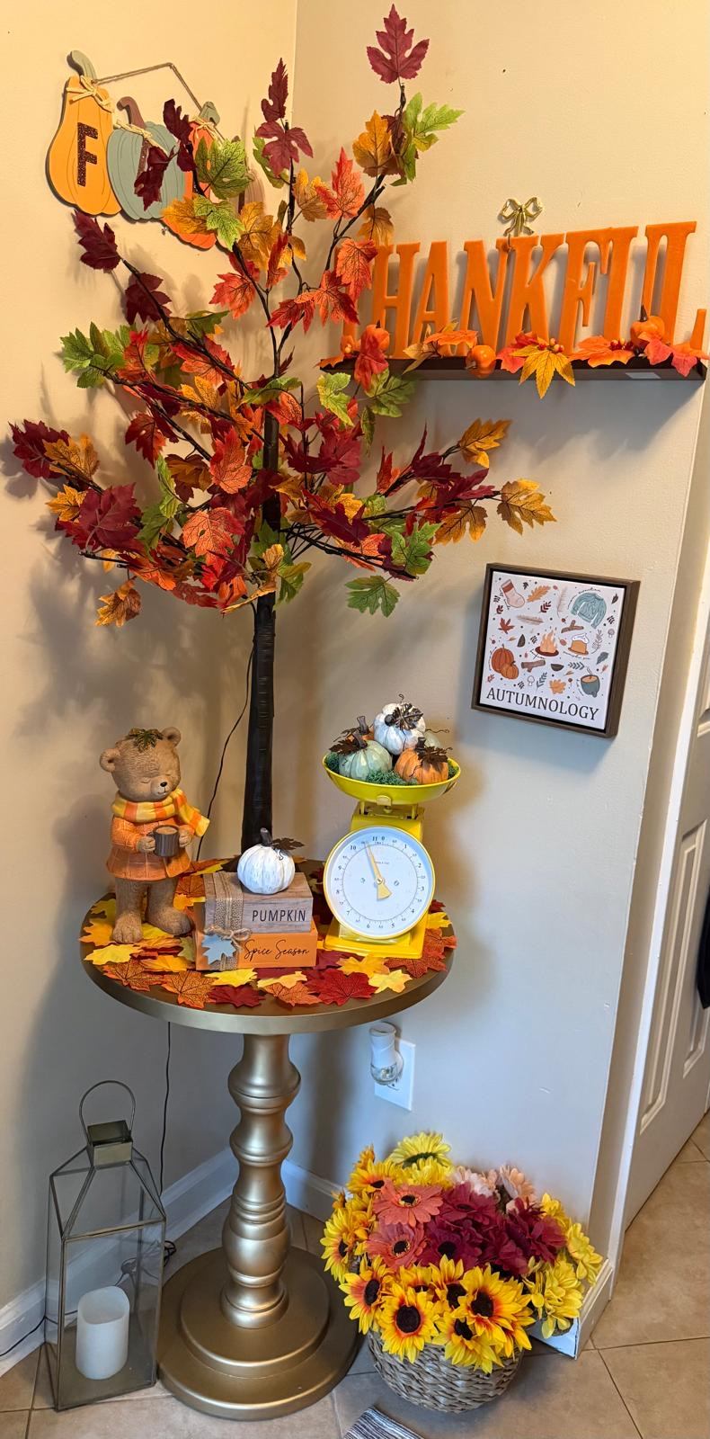 Fall corner display with a lighted leaf tree, bear figurine, and pumpkin scale