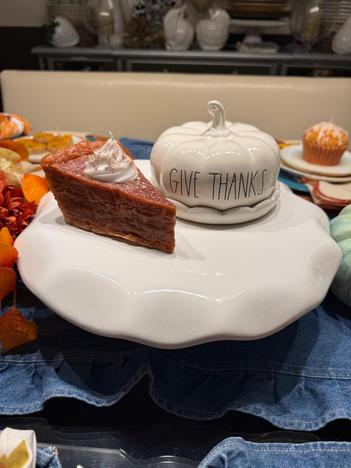 Slice of pumpkin pie beside a Give Thanks pumpkin jar on a cake stand