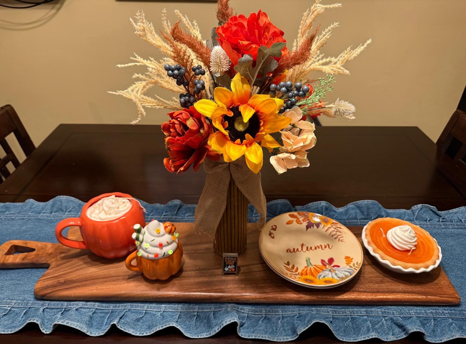 Fall floral arrangement with sunflowers and red peonies beside pumpkin spice mugs and pie