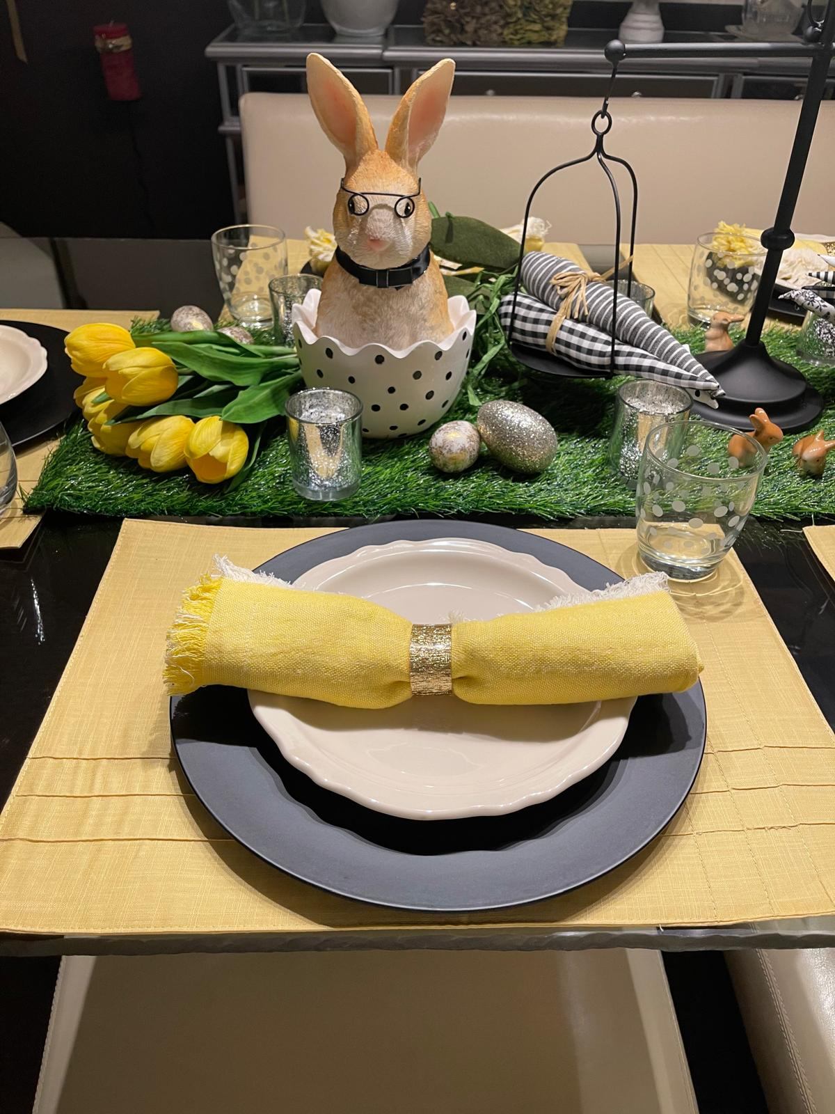 Easter bunny in glasses sitting in a polka dot egg with yellow tulips