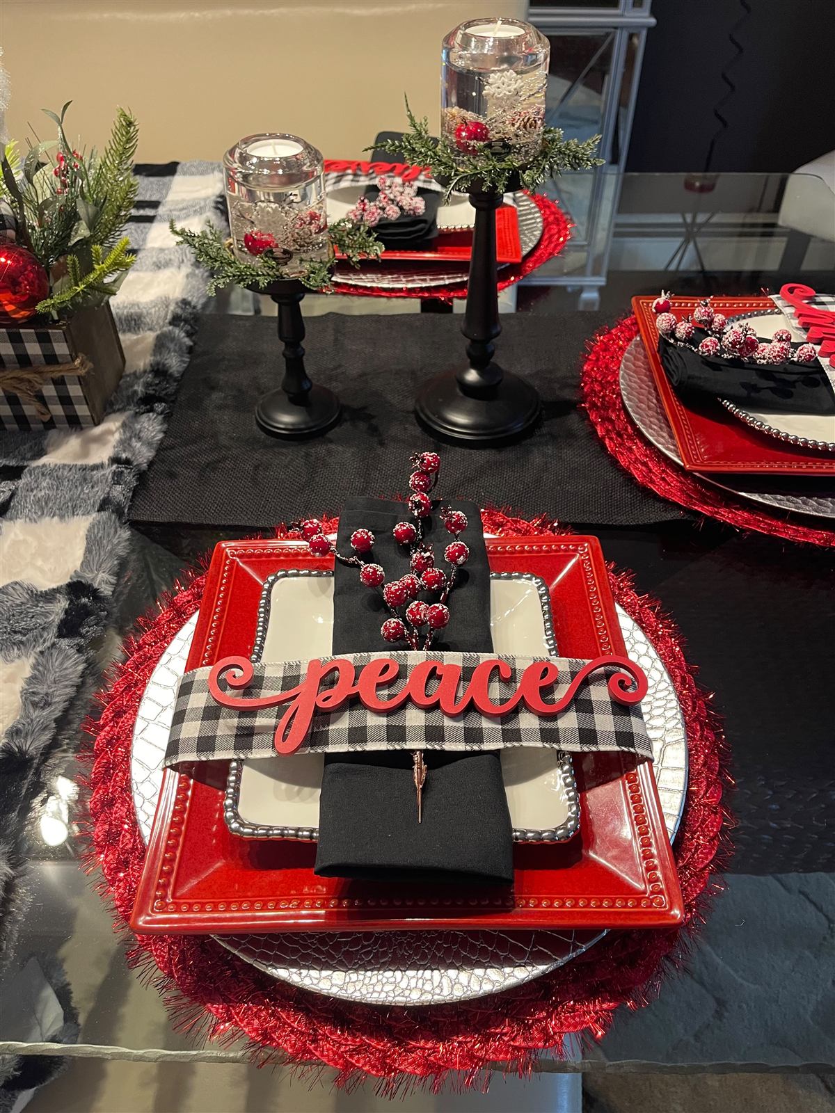 Red, black, and buffalo check holiday table setting with a 'peace' sign
