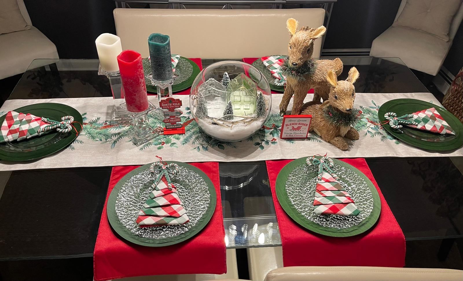 Christmas tablescape with reindeer figurines, candy cane napkins, and a snow globe centerpiece