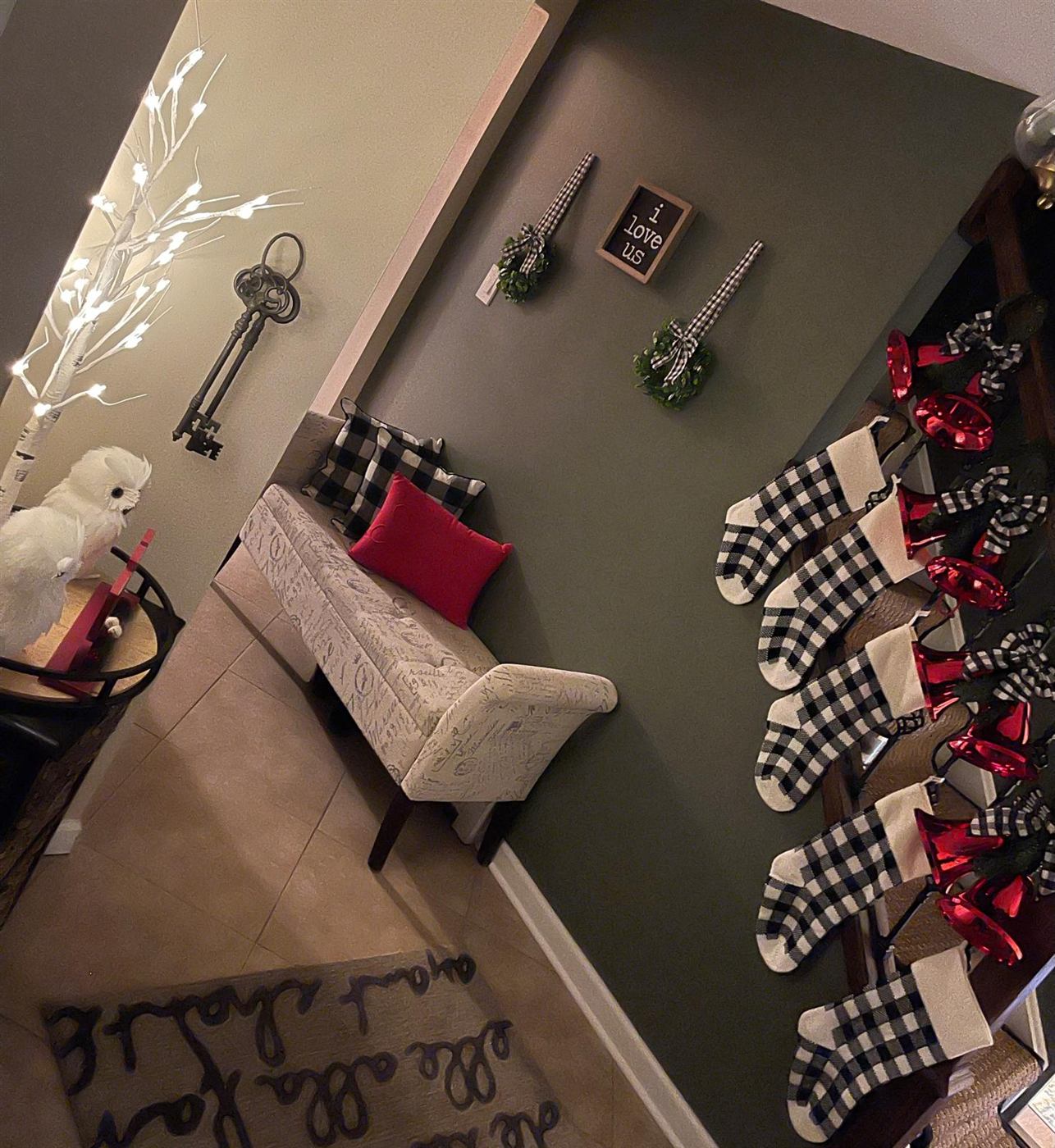 Entryway styled for the holidays with buffalo check stockings and a lit birch tree