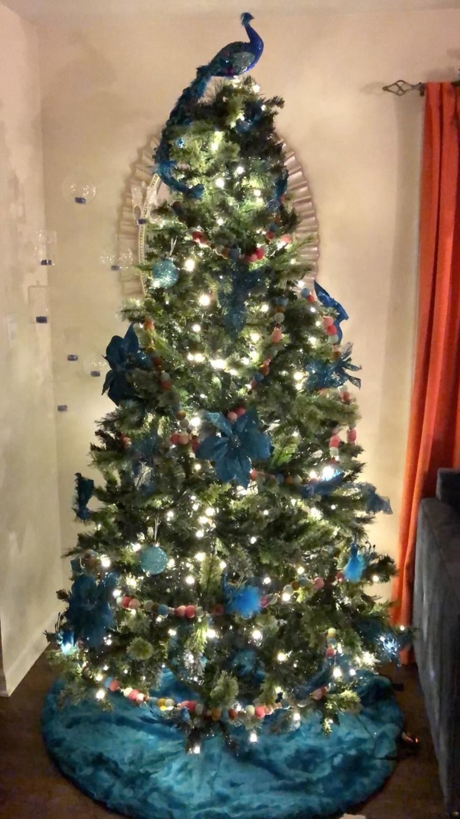 Christmas tree decorated in teal and blush with a glittered peacock topper