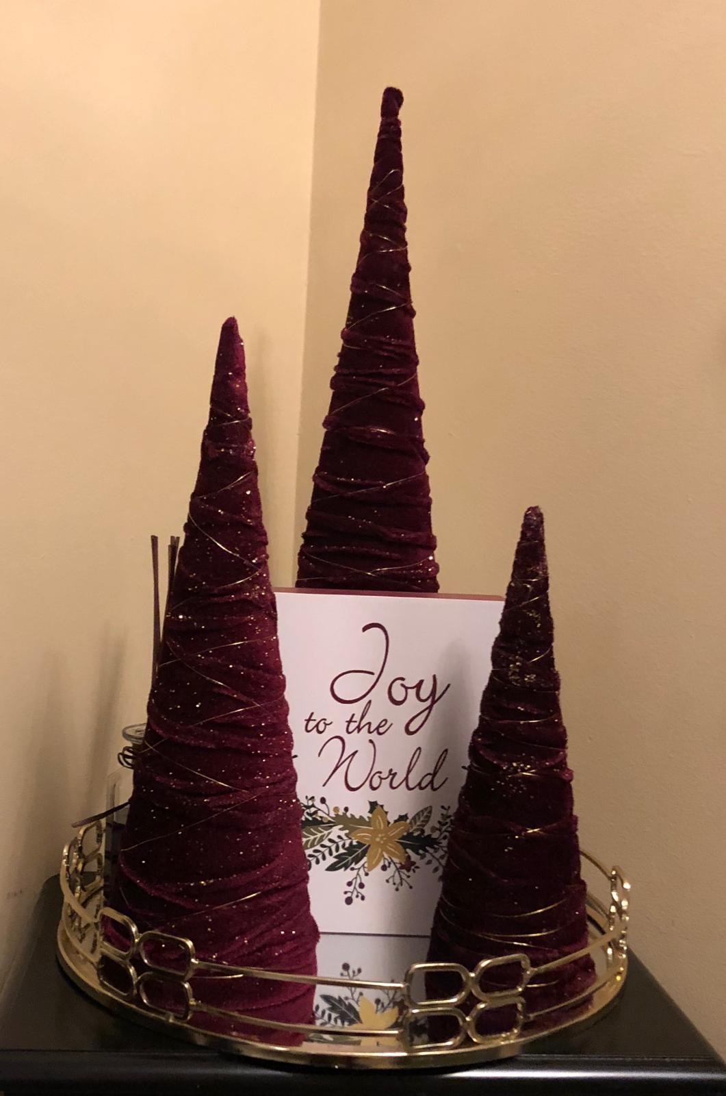 Three burgundy velvet cone trees with a Joy to the World holiday card